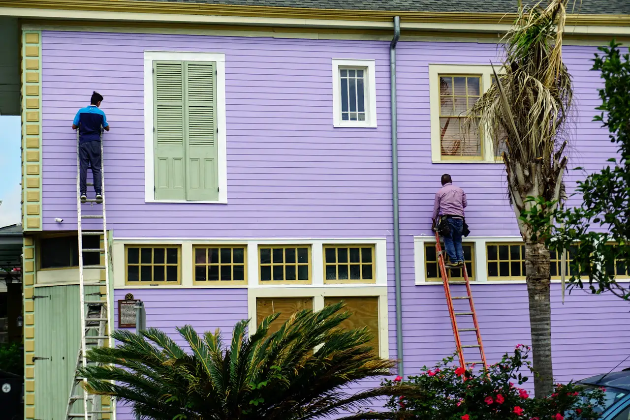 Two painters on ladders finishing an exterior repaint